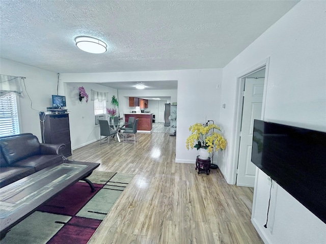 living room with a textured ceiling, light hardwood / wood-style flooring, and plenty of natural light