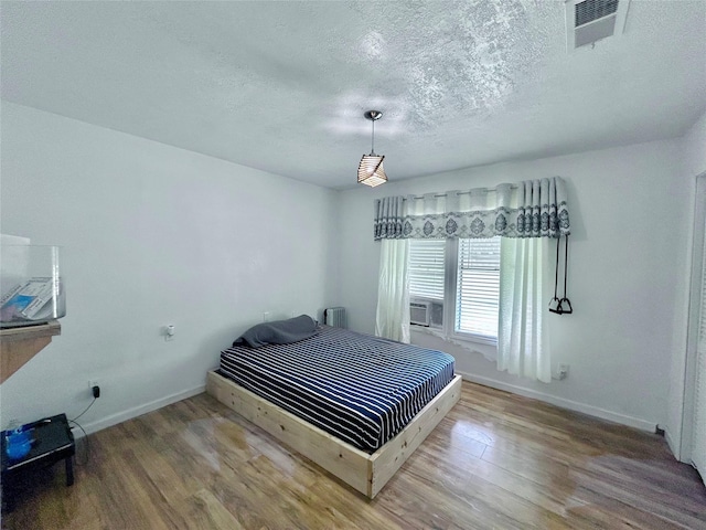 bedroom with radiator, a textured ceiling, and hardwood / wood-style flooring