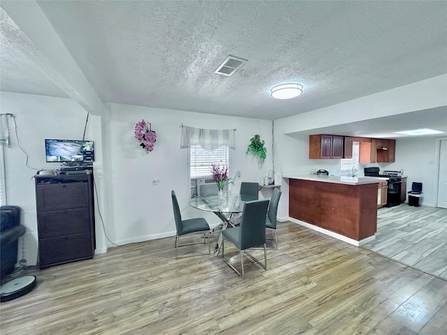 dining area with cooling unit, light wood-type flooring, and a textured ceiling