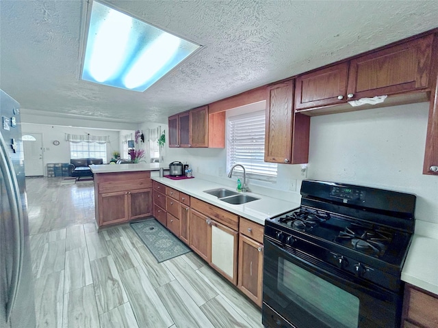 kitchen with sink, a textured ceiling, light wood-type flooring, kitchen peninsula, and black gas range oven