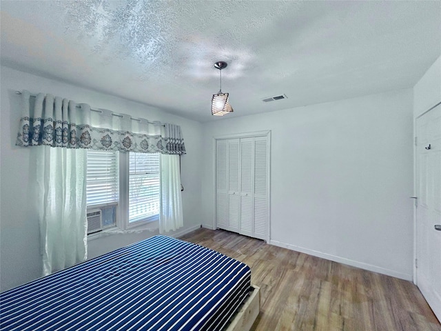 unfurnished bedroom with a textured ceiling, a closet, and wood-type flooring