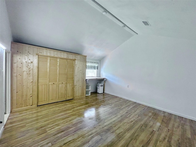 unfurnished bedroom featuring light hardwood / wood-style floors, a closet, and lofted ceiling