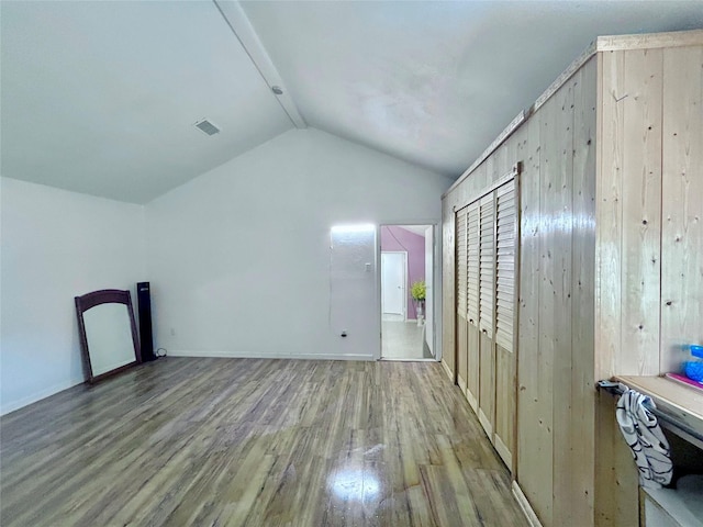 bonus room with lofted ceiling, wooden walls, and light hardwood / wood-style flooring