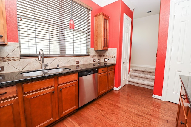 kitchen featuring dishwasher, dark stone countertops, light hardwood / wood-style floors, decorative backsplash, and sink