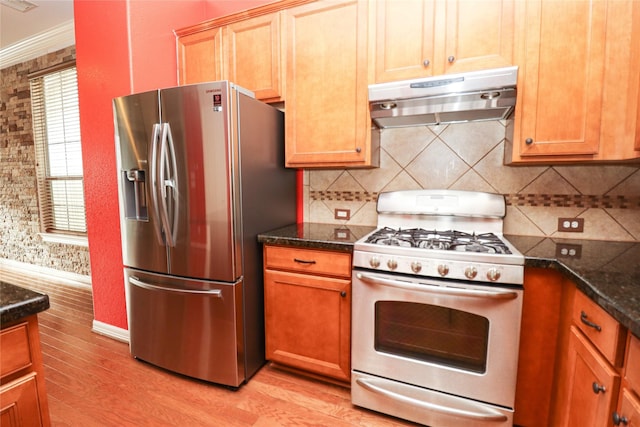 kitchen featuring stainless steel appliances, ornamental molding, light hardwood / wood-style flooring, backsplash, and dark stone counters