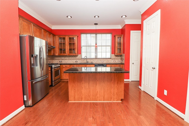 kitchen featuring appliances with stainless steel finishes, tasteful backsplash, a kitchen island, and hanging light fixtures