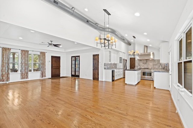 kitchen with stainless steel appliances, pendant lighting, decorative backsplash, wall chimney exhaust hood, and white cabinets