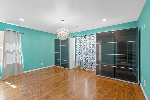 empty room featuring hardwood / wood-style floors and a notable chandelier