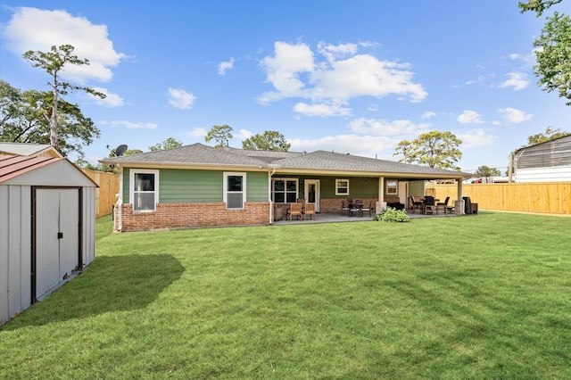 rear view of property featuring a lawn, a patio area, and a storage unit