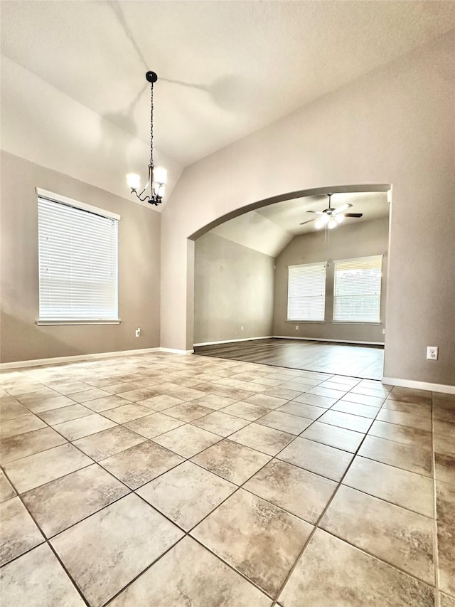 tiled empty room with ceiling fan with notable chandelier and vaulted ceiling