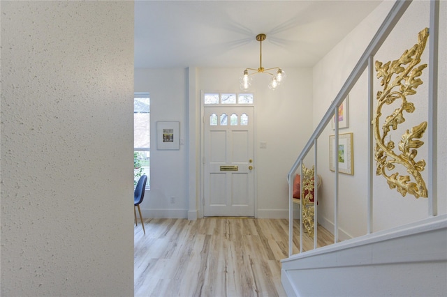 foyer entrance with light hardwood / wood-style floors and a notable chandelier