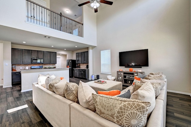 living room featuring a high ceiling, ceiling fan, and dark hardwood / wood-style flooring