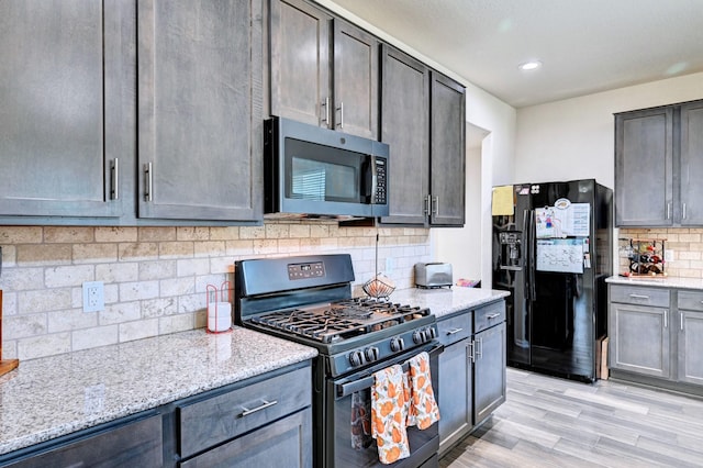 kitchen featuring black appliances, light hardwood / wood-style floors, backsplash, and light stone countertops