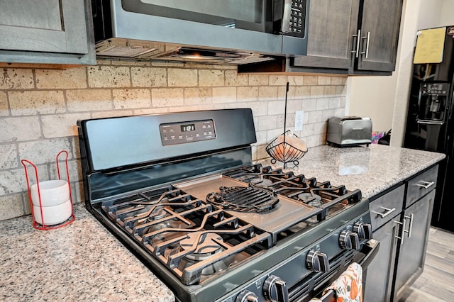 kitchen featuring light wood-type flooring, black appliances, and light stone countertops