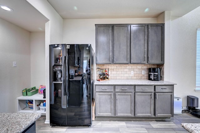 kitchen featuring light hardwood / wood-style flooring, black refrigerator with ice dispenser, backsplash, and light stone countertops