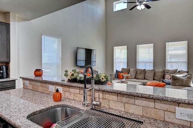 kitchen featuring light stone counters, ceiling fan, and a wealth of natural light