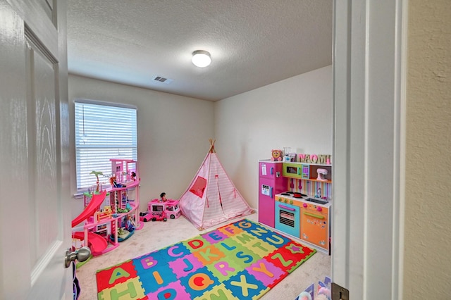 recreation room featuring a textured ceiling and carpet