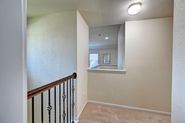 hall featuring a textured ceiling and light carpet