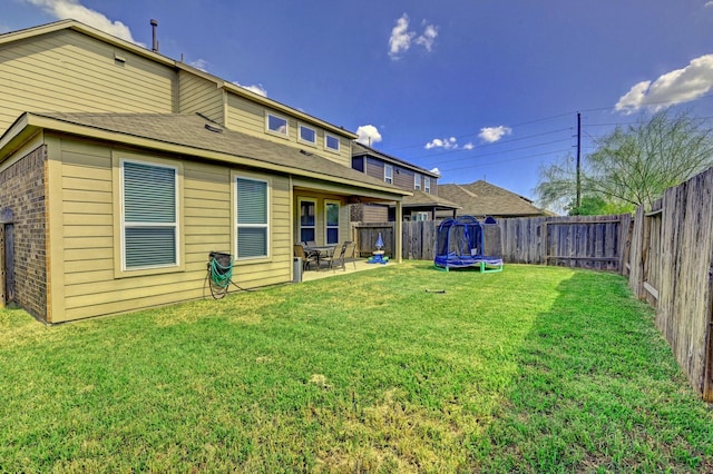 back of house featuring a lawn, a patio area, and a trampoline