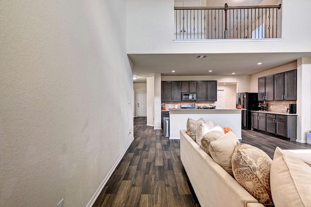 living room featuring a high ceiling and dark wood-type flooring