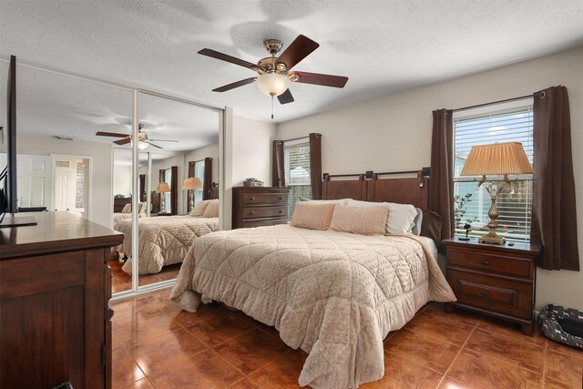 tiled bedroom with a textured ceiling, a closet, and ceiling fan