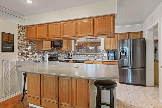 kitchen with sink, light tile patterned floors, a kitchen breakfast bar, black appliances, and kitchen peninsula