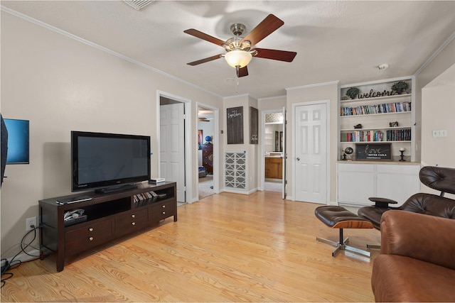 living room with built in shelves, ceiling fan, ornamental molding, and light hardwood / wood-style floors