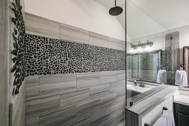 bathroom with vaulted ceiling, tiled shower, and vanity