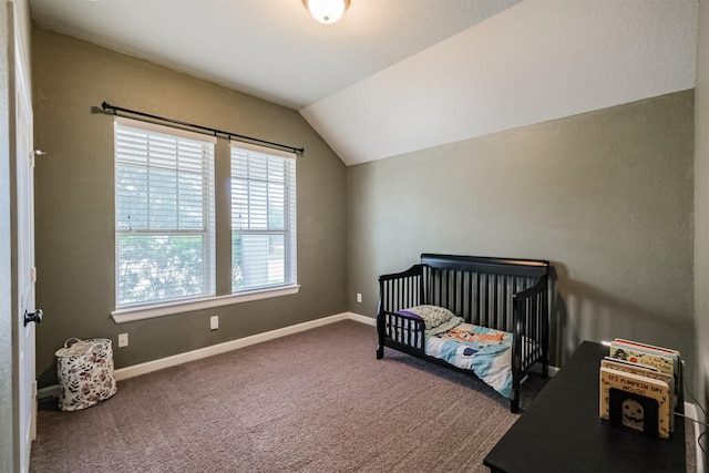 bedroom with a nursery area, carpet flooring, and vaulted ceiling