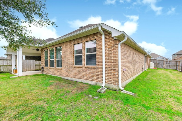 view of side of home featuring ceiling fan and a lawn