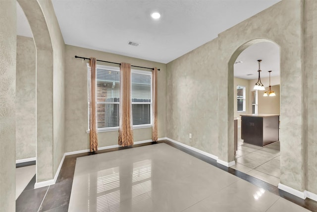 empty room featuring tile patterned floors and an inviting chandelier