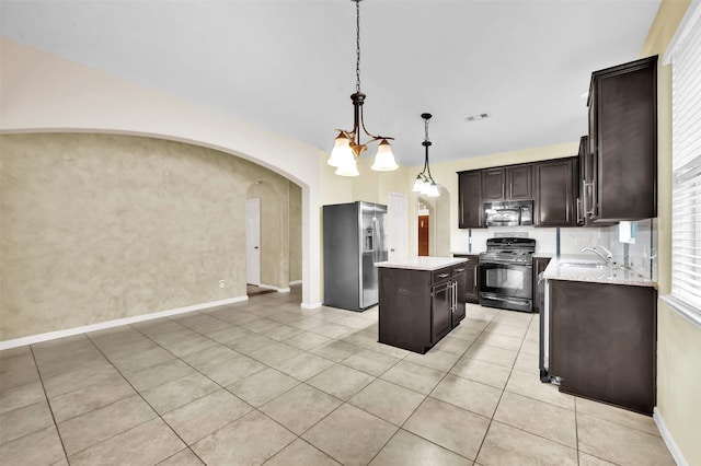 kitchen with pendant lighting, gas stove, a kitchen island, stainless steel fridge with ice dispenser, and dark brown cabinets