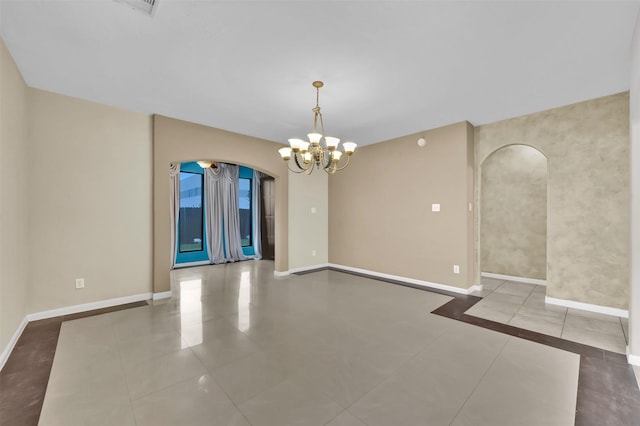 tiled spare room with a chandelier