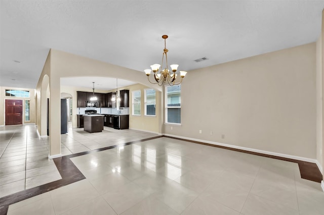 unfurnished living room with light tile patterned floors and an inviting chandelier