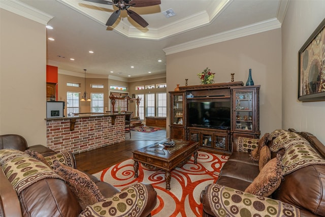 living room with ceiling fan, ornamental molding, a tray ceiling, and hardwood / wood-style floors