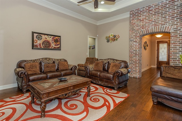 living room featuring a raised ceiling, ornamental molding, ceiling fan, and dark wood-type flooring