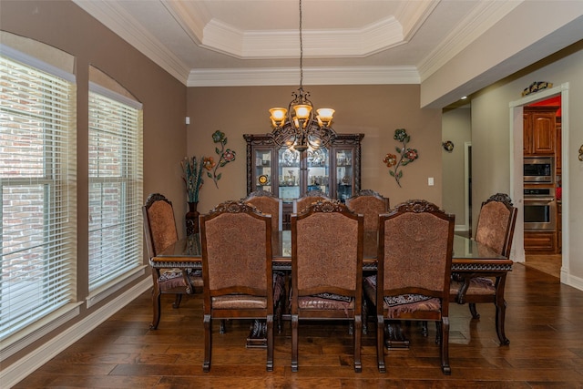 dining room featuring an inviting chandelier, ornamental molding, a tray ceiling, and dark hardwood / wood-style floors