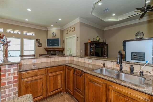 kitchen with sink, stone countertops, ceiling fan, and crown molding