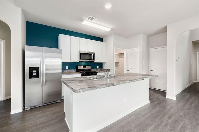 kitchen with an island with sink, white cabinets, appliances with stainless steel finishes, wood-type flooring, and sink