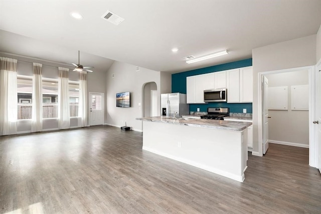 kitchen featuring light stone counters, stainless steel appliances, a center island with sink, white cabinets, and ceiling fan