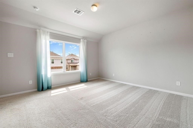 carpeted spare room featuring vaulted ceiling