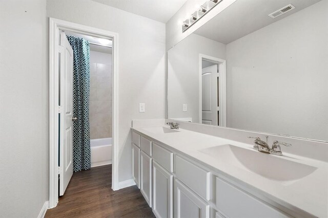 bathroom with shower / bathtub combination with curtain, hardwood / wood-style floors, and vanity