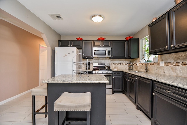 kitchen featuring a kitchen bar, a kitchen island, decorative backsplash, appliances with stainless steel finishes, and sink