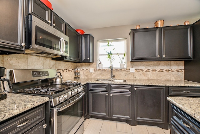 kitchen featuring stainless steel appliances, sink, light stone counters, light tile patterned flooring, and tasteful backsplash