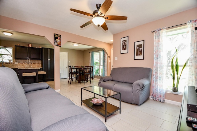 living room featuring light tile patterned floors, ceiling fan, and plenty of natural light