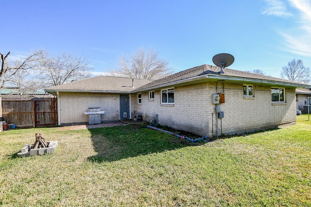 back of property with an outdoor fire pit and a lawn