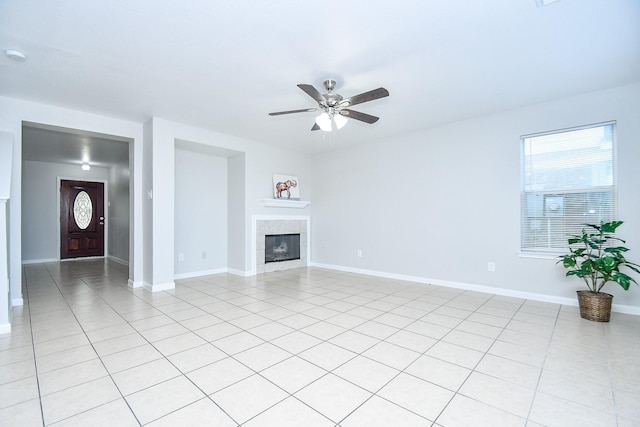 unfurnished living room featuring a tiled fireplace, ceiling fan, and light tile patterned floors