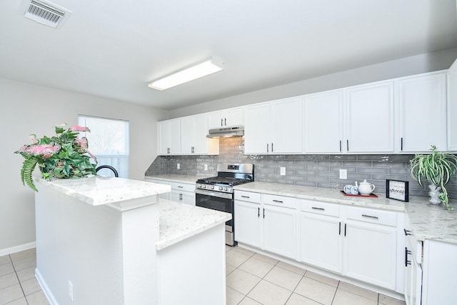 kitchen with white cabinetry, stainless steel gas range oven, backsplash, light stone countertops, and a center island with sink