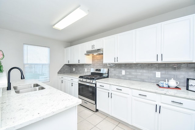 kitchen with light stone counters, white cabinets, gas stove, and sink