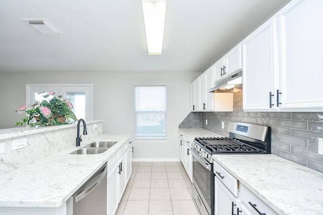 kitchen featuring white cabinets, stainless steel appliances, light tile patterned floors, decorative backsplash, and sink